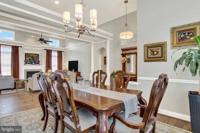 dining room featuring arched walkways, a glass covered fireplace, visible vents, and hardwood / wood-style floors