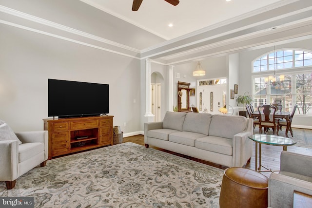 living room with ceiling fan with notable chandelier, crown molding, baseboards, and wood finished floors