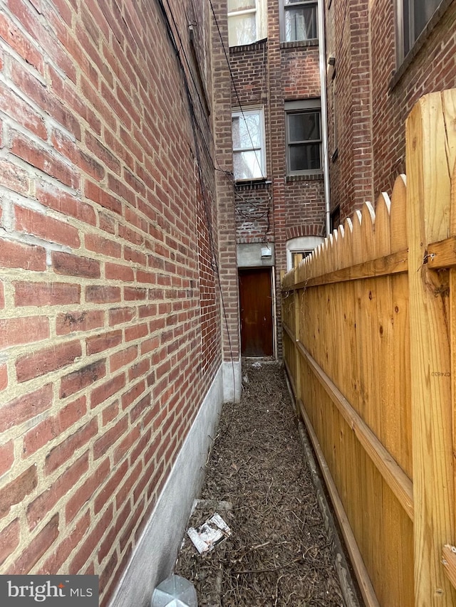 view of side of property with brick siding and fence