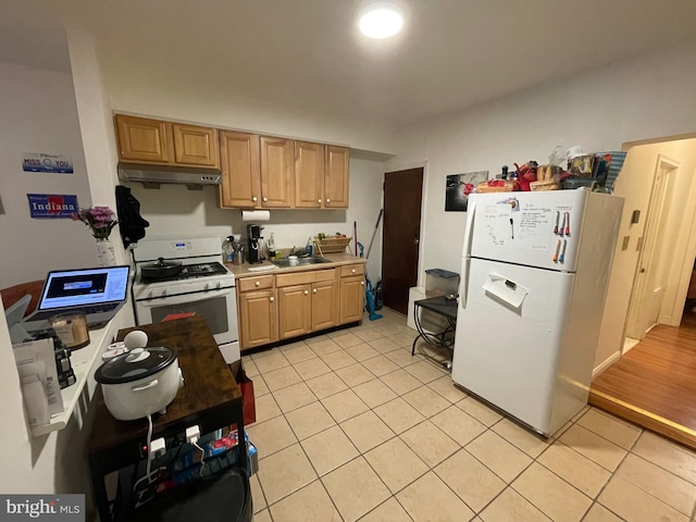 kitchen with under cabinet range hood, light countertops, light tile patterned floors, white appliances, and a sink