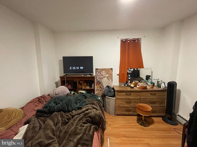 bedroom featuring a baseboard heating unit and light wood finished floors