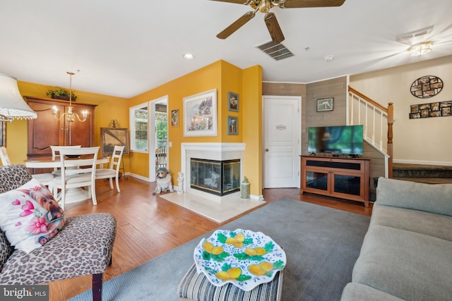 living room featuring stairs, baseboards, a ceiling fan, wood finished floors, and a multi sided fireplace