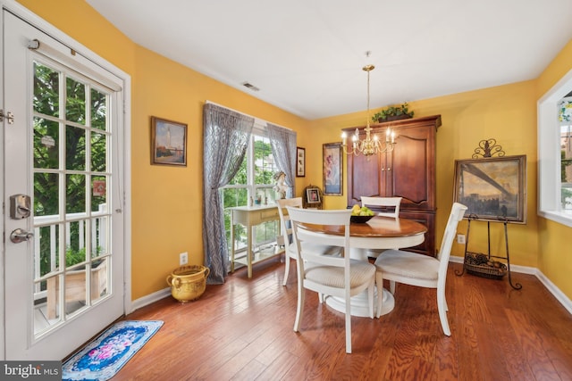 dining space featuring a chandelier, wood finished floors, and baseboards