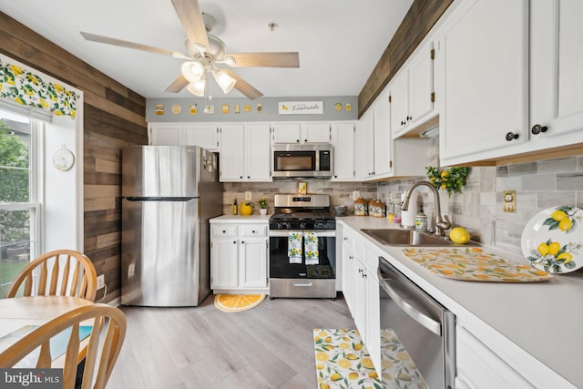 kitchen featuring stainless steel appliances, a sink, backsplash, light countertops, and wood walls
