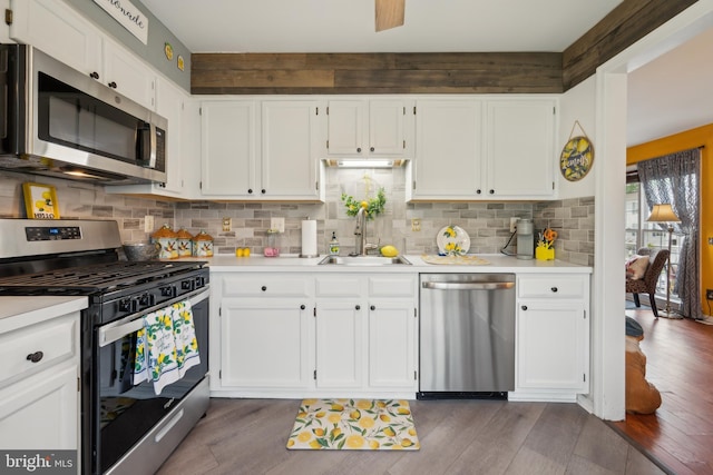 kitchen with stainless steel appliances, a sink, dark wood-style floors, light countertops, and white cabinets