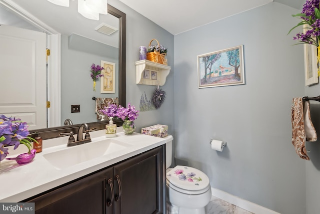 bathroom with marble finish flooring, toilet, vanity, and baseboards