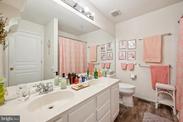 full bathroom featuring wood finished floors, toilet, and double vanity
