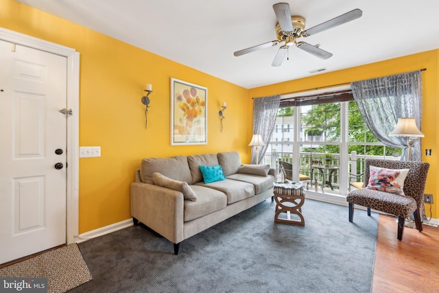 living room with ceiling fan, baseboards, and wood finished floors