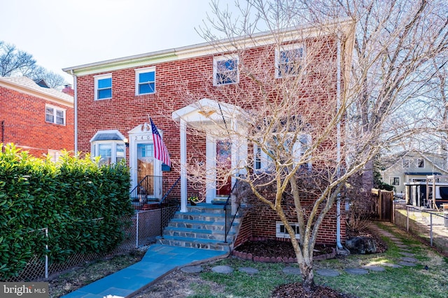 view of front of home featuring fence and brick siding