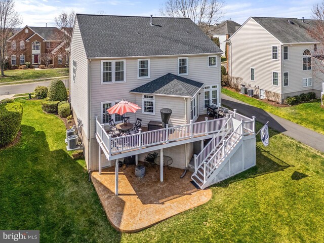rear view of property featuring a yard, cooling unit, a wooden deck, and roof with shingles