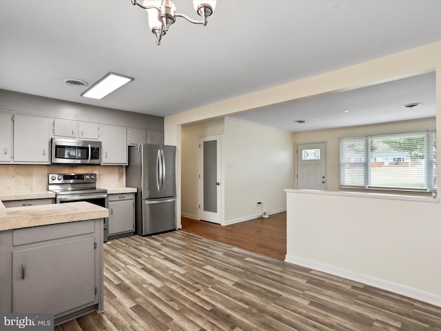 kitchen with appliances with stainless steel finishes, light countertops, visible vents, and wood finished floors