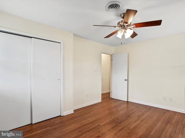 unfurnished bedroom with a closet, visible vents, ceiling fan, wood finished floors, and baseboards