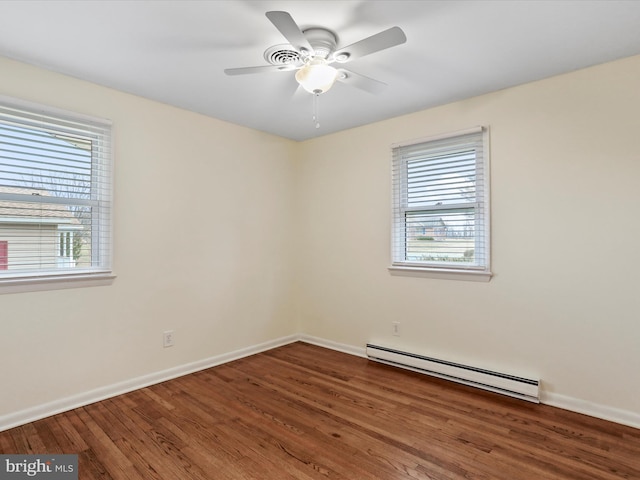 spare room featuring a baseboard heating unit, ceiling fan, wood finished floors, and baseboards