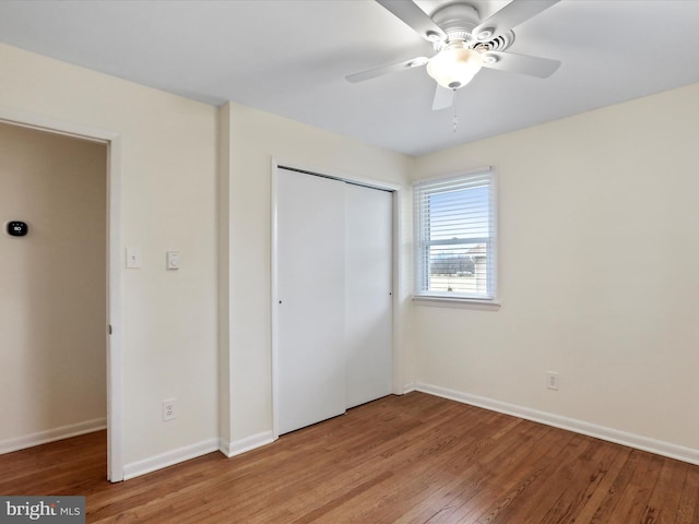 unfurnished bedroom featuring light wood finished floors, ceiling fan, baseboards, and a closet