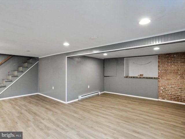 finished basement featuring stairway, baseboard heating, and wood finished floors