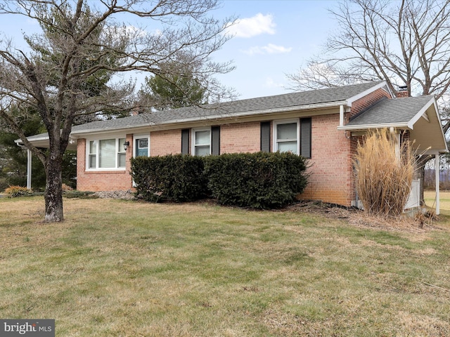 view of front facade featuring roof with shingles, a chimney, a front lawn, and brick siding