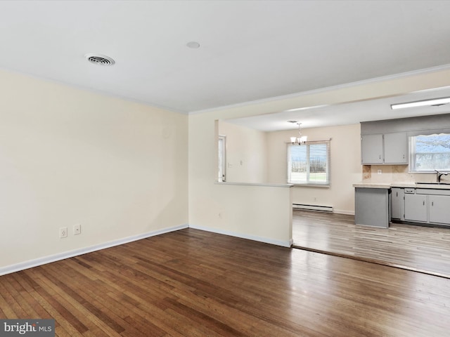 unfurnished living room featuring a baseboard radiator, visible vents, a chandelier, and wood finished floors