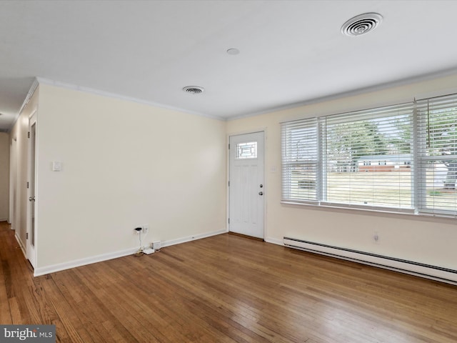 foyer with visible vents, baseboards, wood-type flooring, crown molding, and a baseboard heating unit