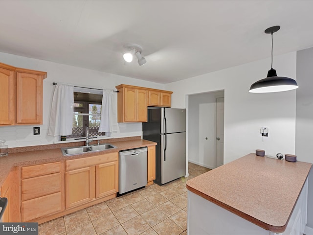 kitchen featuring light brown cabinetry, appliances with stainless steel finishes, a sink, and decorative light fixtures