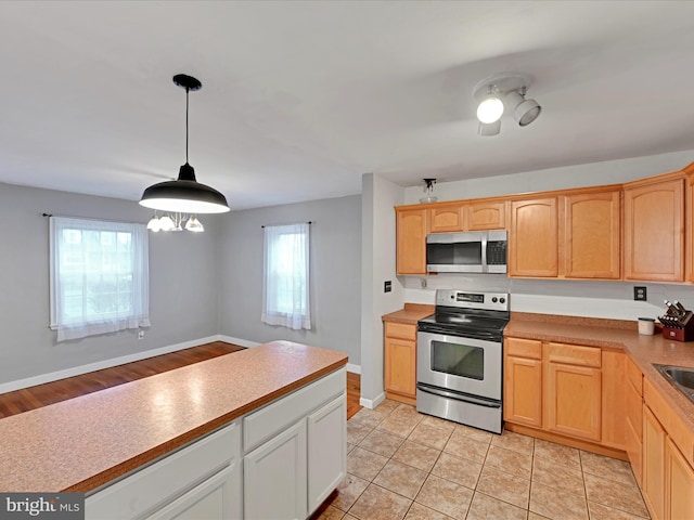 kitchen with hanging light fixtures, light brown cabinets, appliances with stainless steel finishes, and light countertops