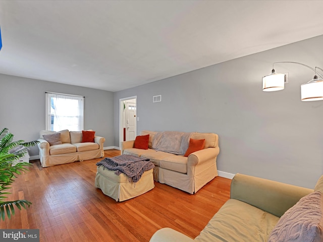 living room featuring hardwood / wood-style flooring, baseboards, and visible vents