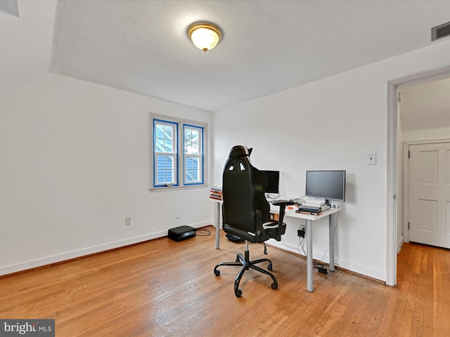 home office featuring visible vents, baseboards, vaulted ceiling, and hardwood / wood-style floors