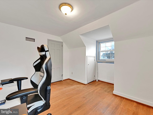 office space featuring light wood-style floors, baseboards, and vaulted ceiling