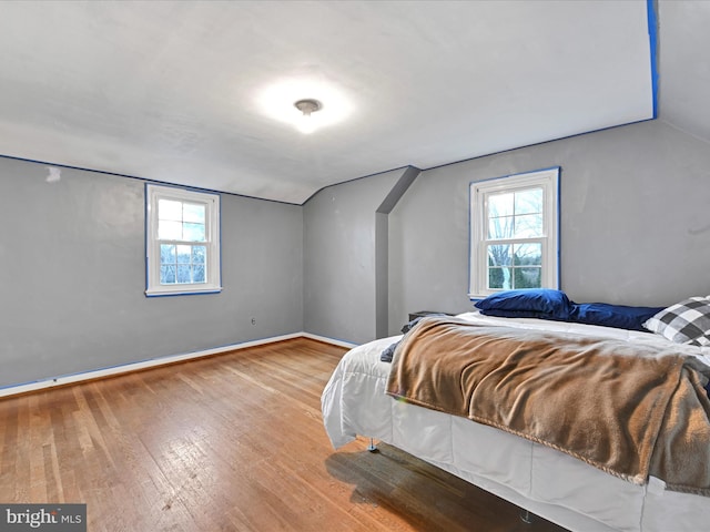 bedroom featuring lofted ceiling, wood finished floors, and baseboards