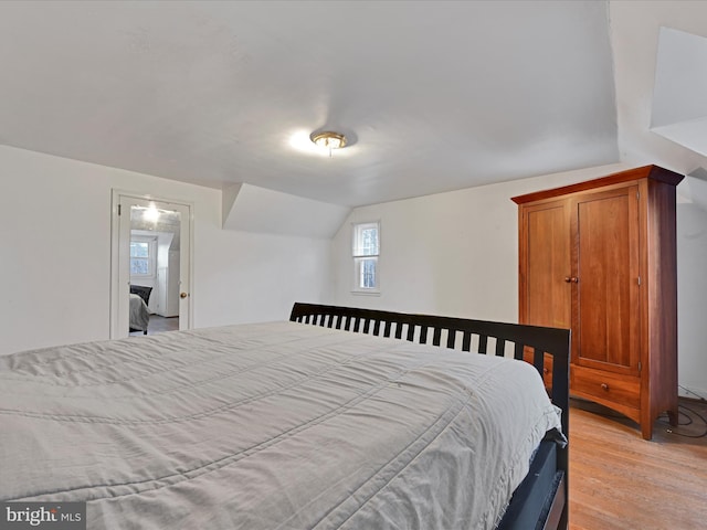 bedroom featuring vaulted ceiling and light wood-type flooring