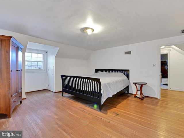 bedroom featuring lofted ceiling, light wood-style floors, baseboards, and visible vents