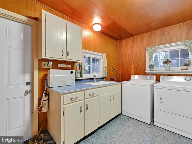 clothes washing area with wooden ceiling, laundry area, wood walls, a sink, and independent washer and dryer