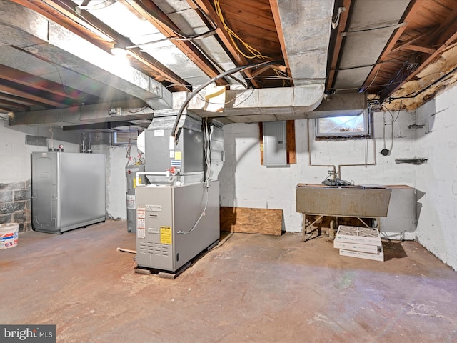 unfinished below grade area featuring electric water heater, refrigerator, a sink, electric panel, and heating unit