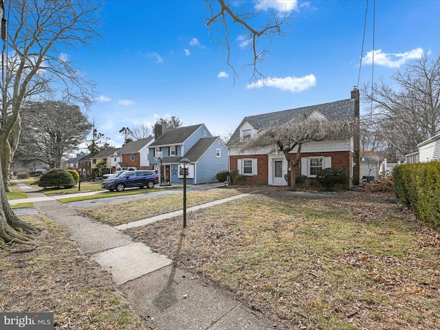 view of front of home featuring a residential view, brick siding, and a chimney