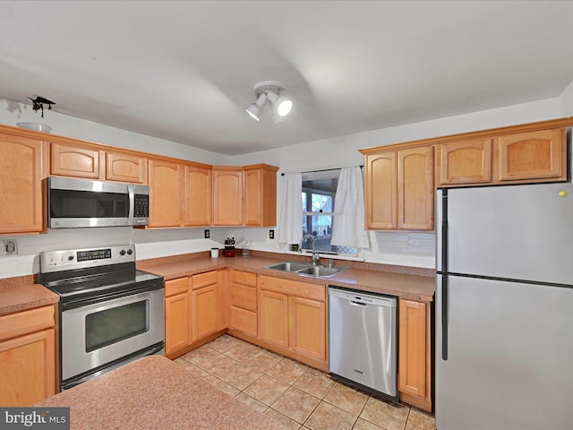 kitchen with stainless steel appliances, light brown cabinetry, a sink, and light tile patterned floors