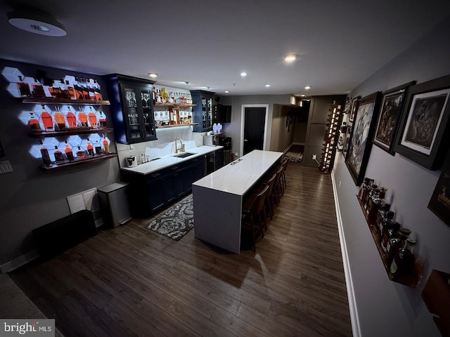 bar featuring a sink, wet bar, recessed lighting, and dark wood-style flooring