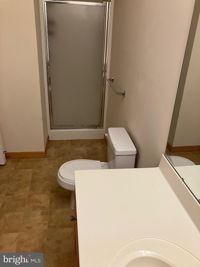 full bath with tile patterned floors, toilet, a shower stall, baseboards, and vanity