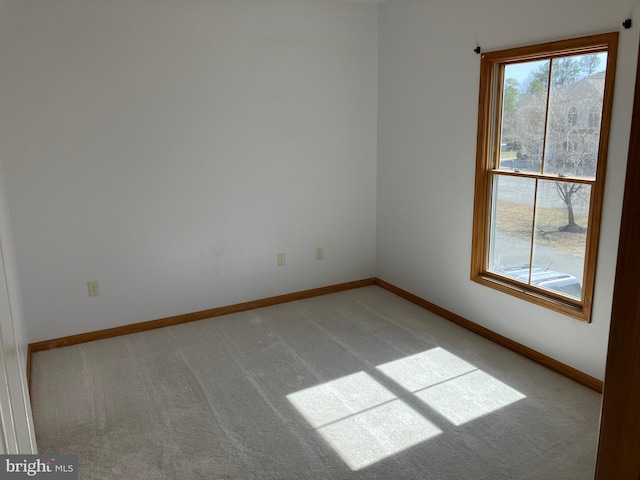 empty room featuring light carpet and baseboards