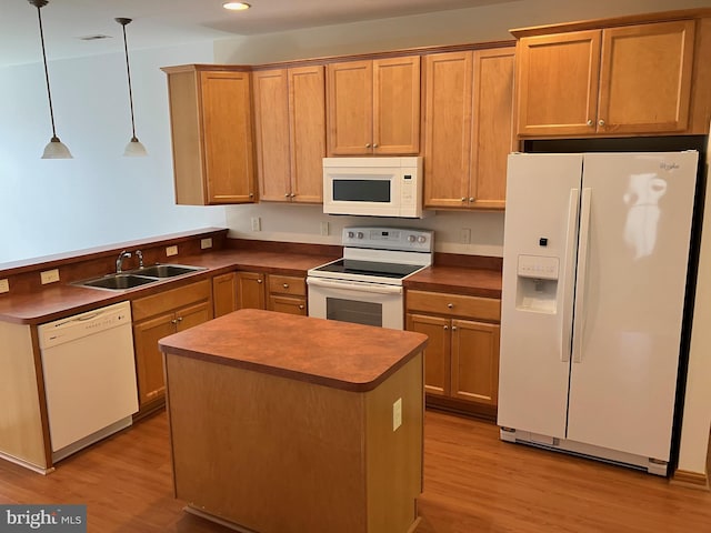 kitchen with a sink, white appliances, dark countertops, and light wood finished floors