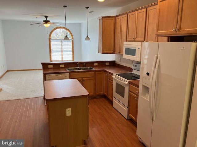 kitchen with white appliances, a peninsula, a sink, pendant lighting, and brown cabinets