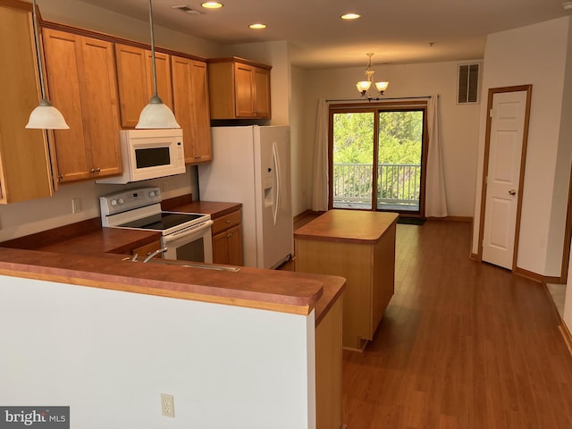 kitchen featuring visible vents, a center island, dark wood finished floors, brown cabinets, and white appliances