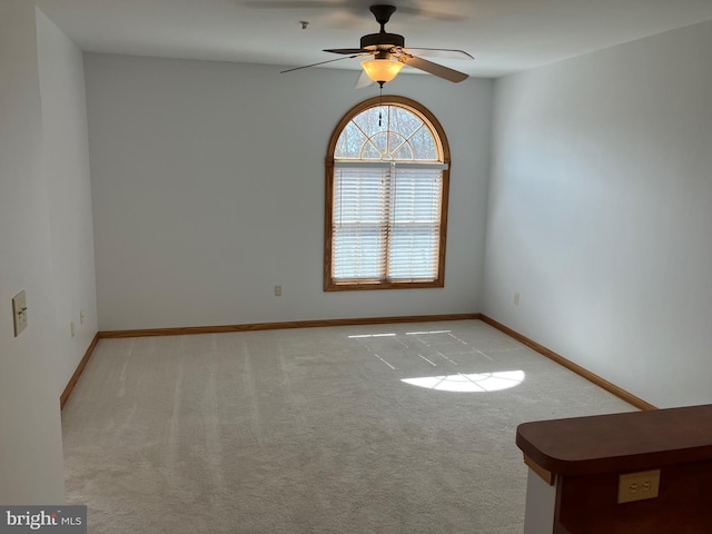 empty room with baseboards, light carpet, and a ceiling fan