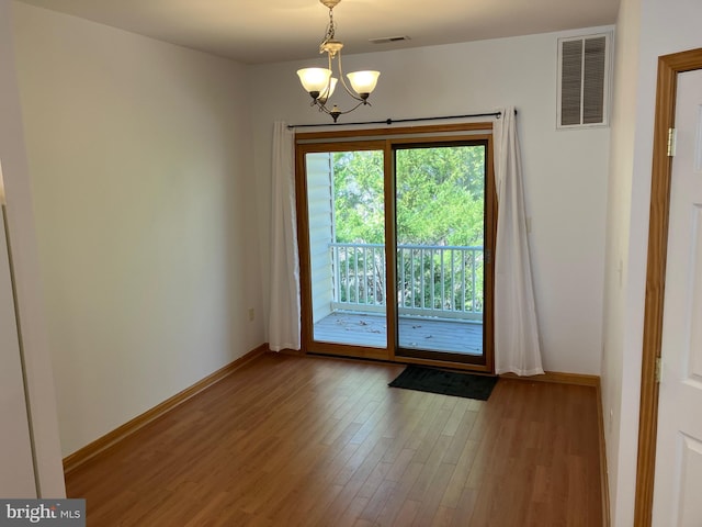 doorway to outside with visible vents, baseboards, an inviting chandelier, and wood finished floors