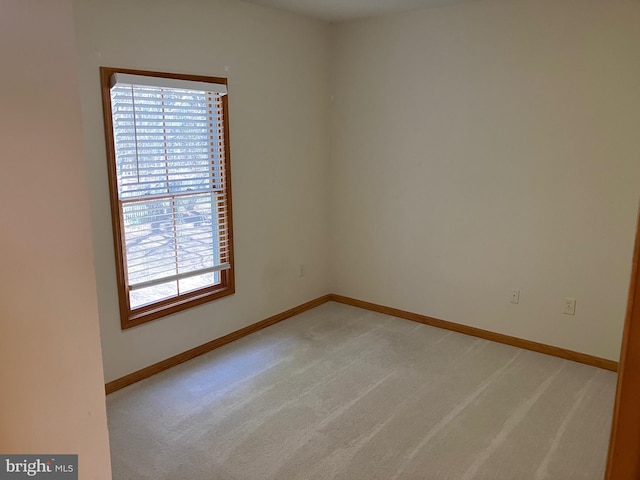 unfurnished room featuring baseboards and light carpet