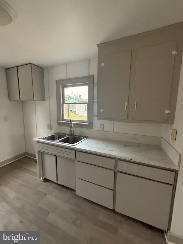 kitchen featuring light wood-style flooring, light stone counters, open shelves, and a sink