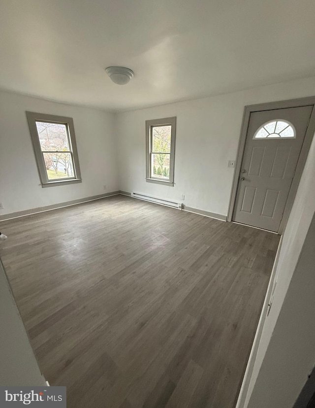 foyer entrance with a baseboard heating unit, baseboards, and wood finished floors