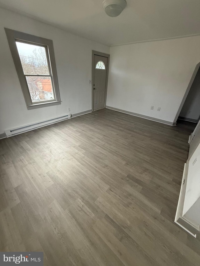 unfurnished living room with baseboards, baseboard heating, and wood finished floors