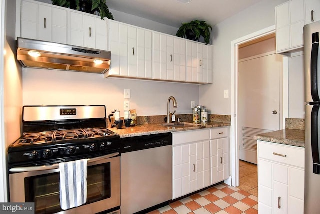 kitchen with white cabinets, appliances with stainless steel finishes, under cabinet range hood, and a sink