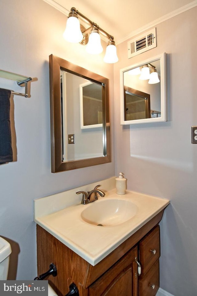 bathroom with vanity, toilet, visible vents, and ornamental molding