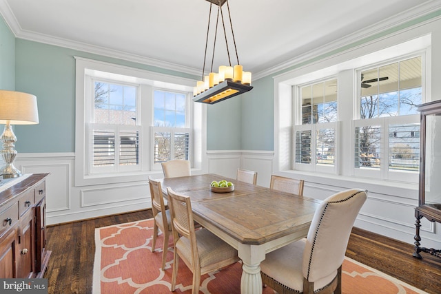 dining area featuring dark wood finished floors, crown molding, and wainscoting