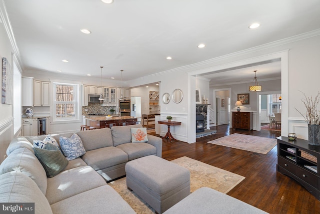 living room featuring dark wood finished floors, recessed lighting, wainscoting, and crown molding